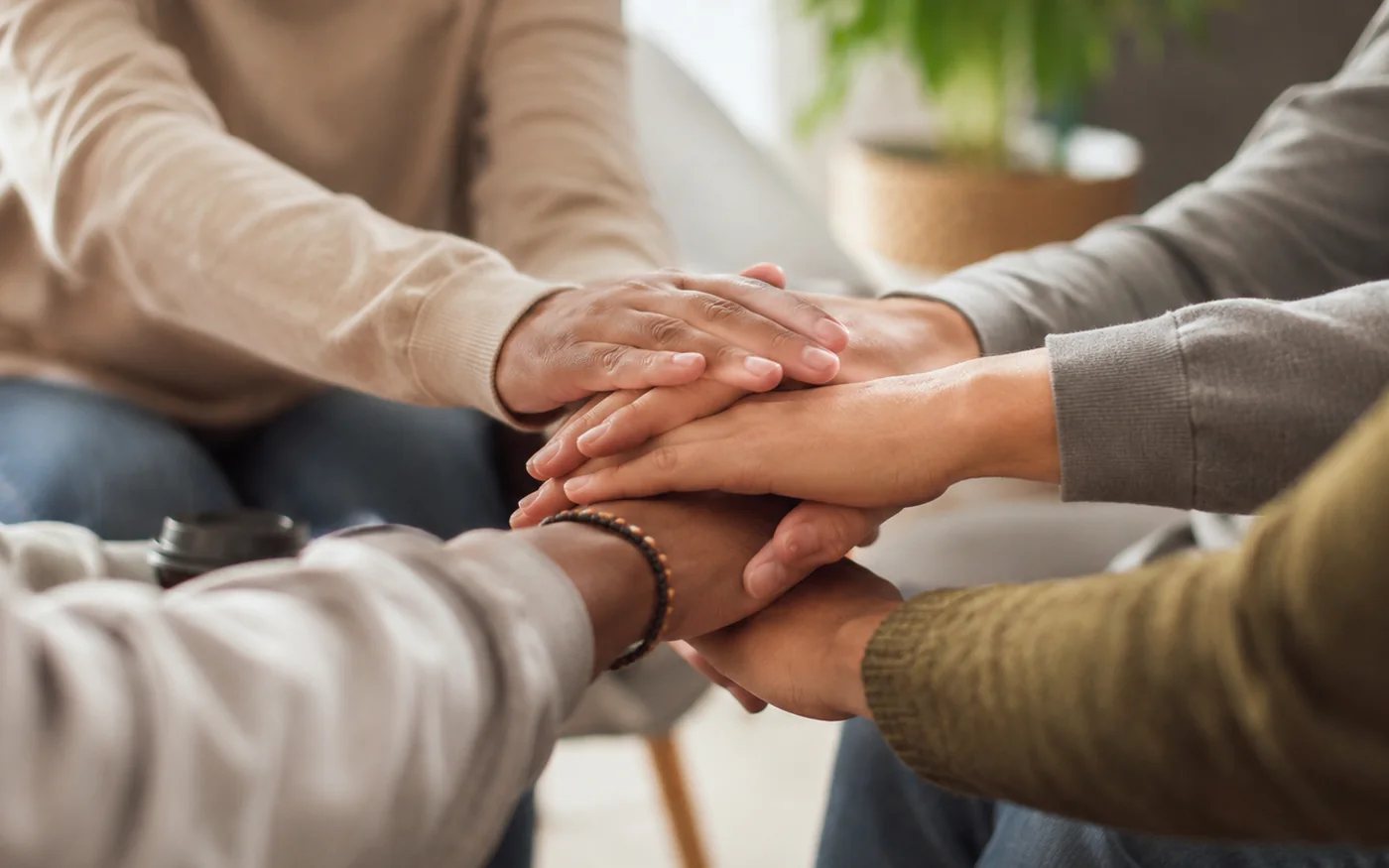 Several people placing their hands together in a supportive group setting.